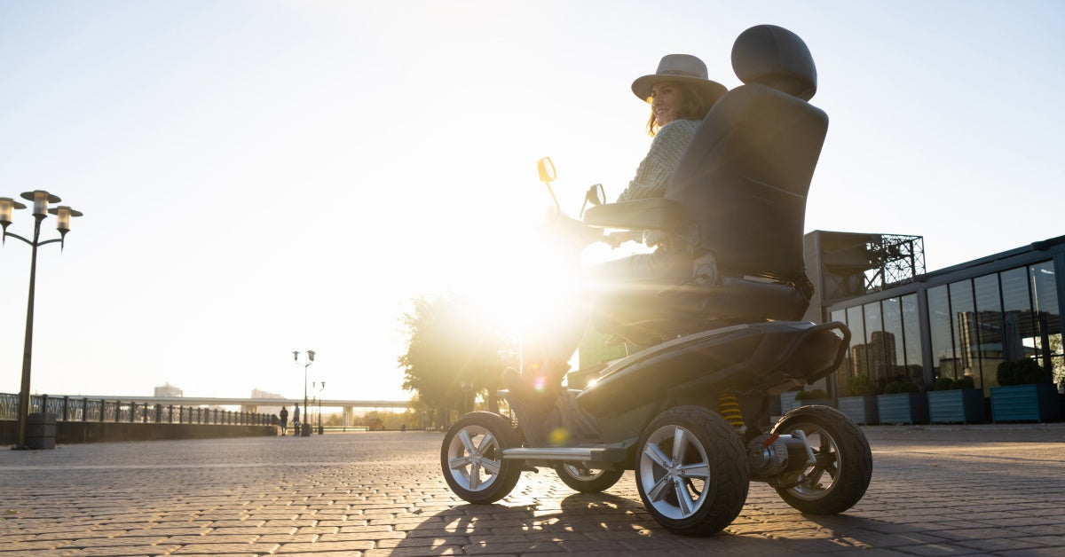 A person wearing a hat and sitting on a red mobility scooter outside. They are looking at a field of colorful flowers.