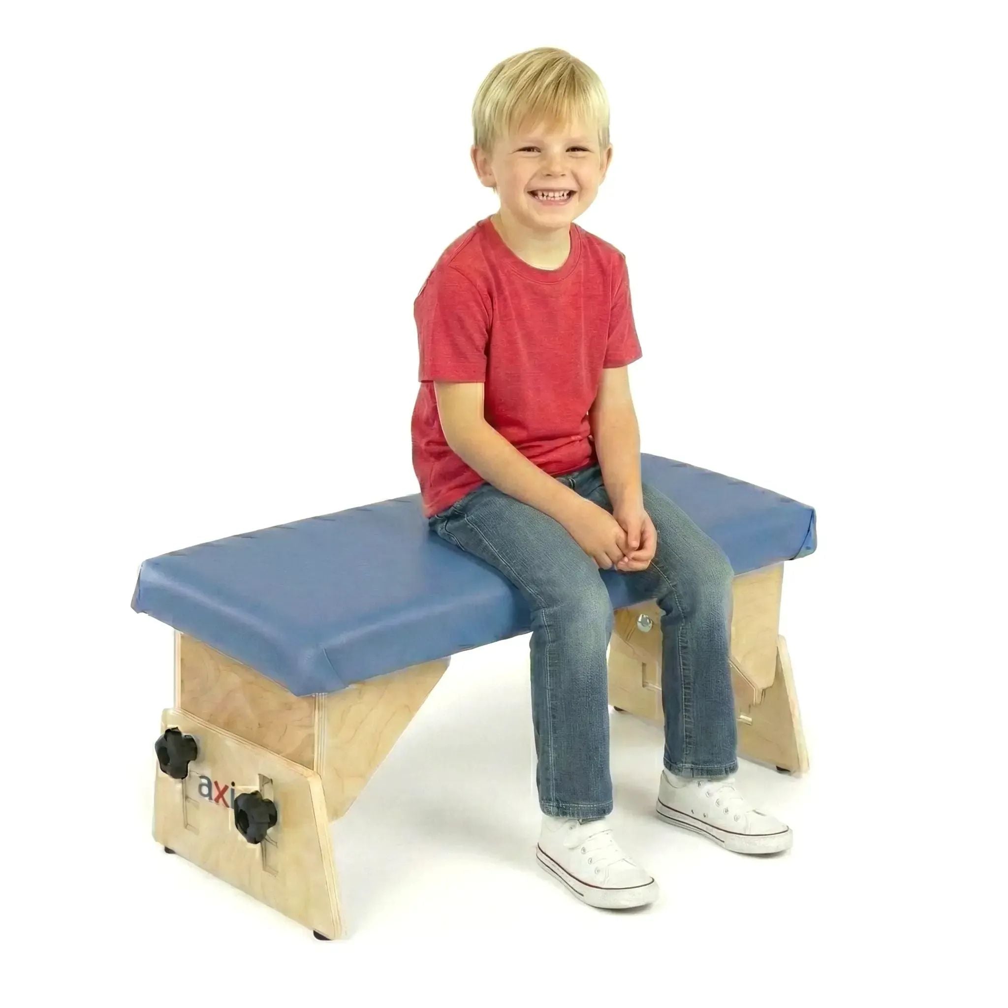 Smiling boy in red shirt sitting with proper posture on blue cushioned Axis therapy bench