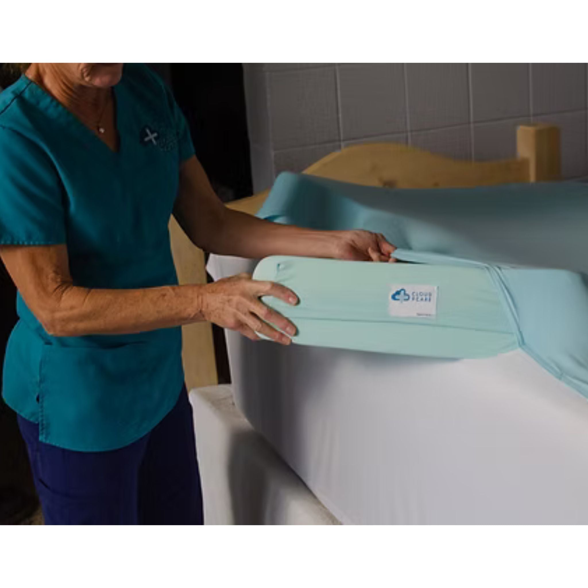 Caregiver inserting a medical-grade foam wedge into the Cloud 9 Care stitched pocket sheet