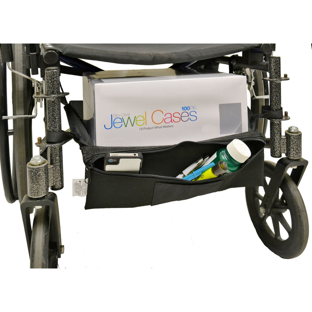 Diestco Cargo Shelf strapped beneath a manual wheelchair seat carrying a boxed package on top, with its built-in zippered pouch open to show a phone, pens, and a small bottle