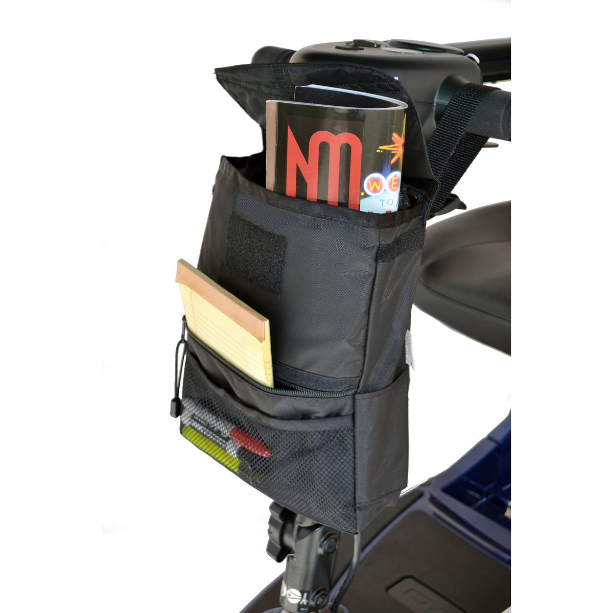 Diestco Deluxe Tiller Bag hanging behind a scooter tiller, loaded with magazines in the main compartment, a notepad in the zippered pocket, and pens in the mesh pocket