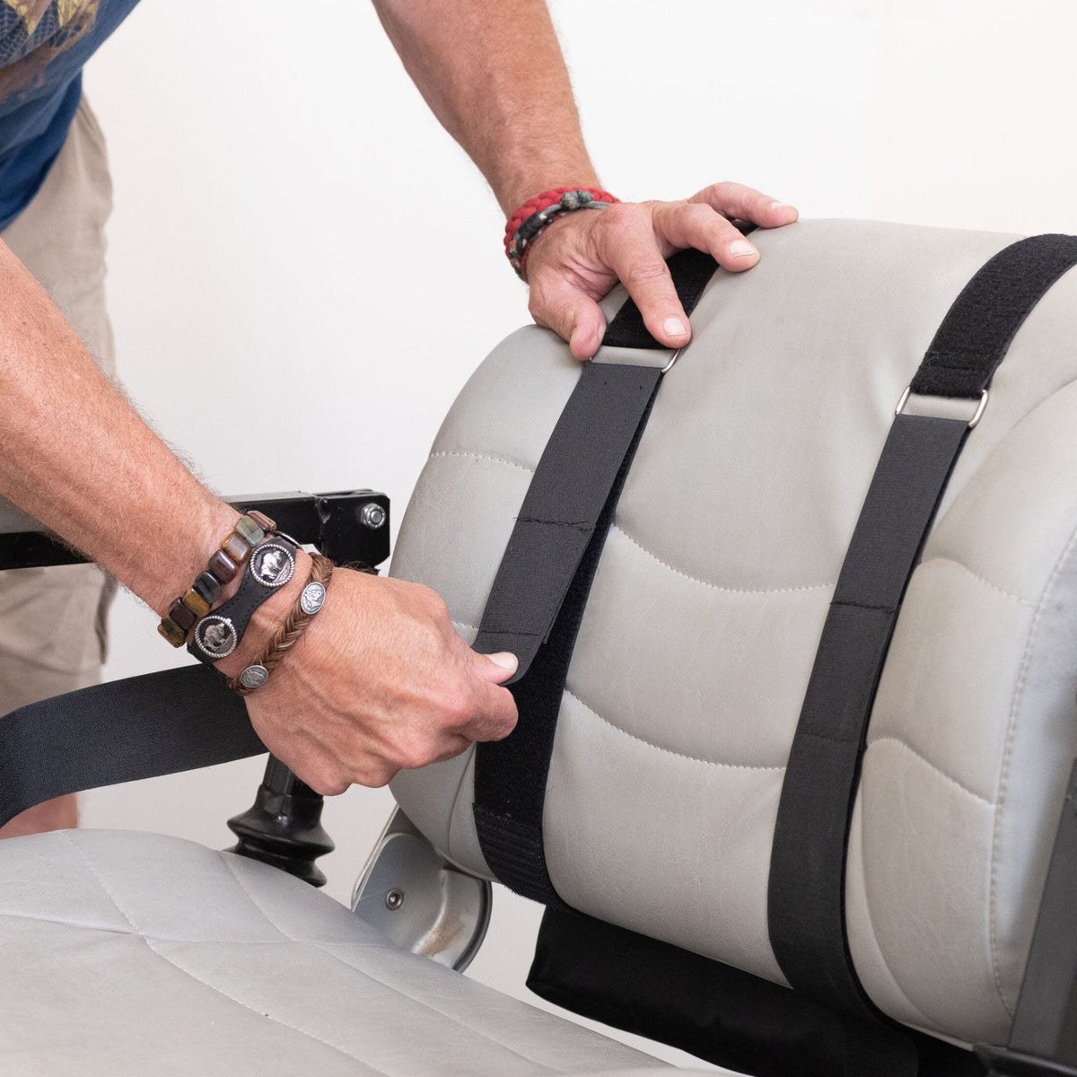 Person threading the Diestco Monster Bag adjustable straps around a scooter captain seatback to mount it