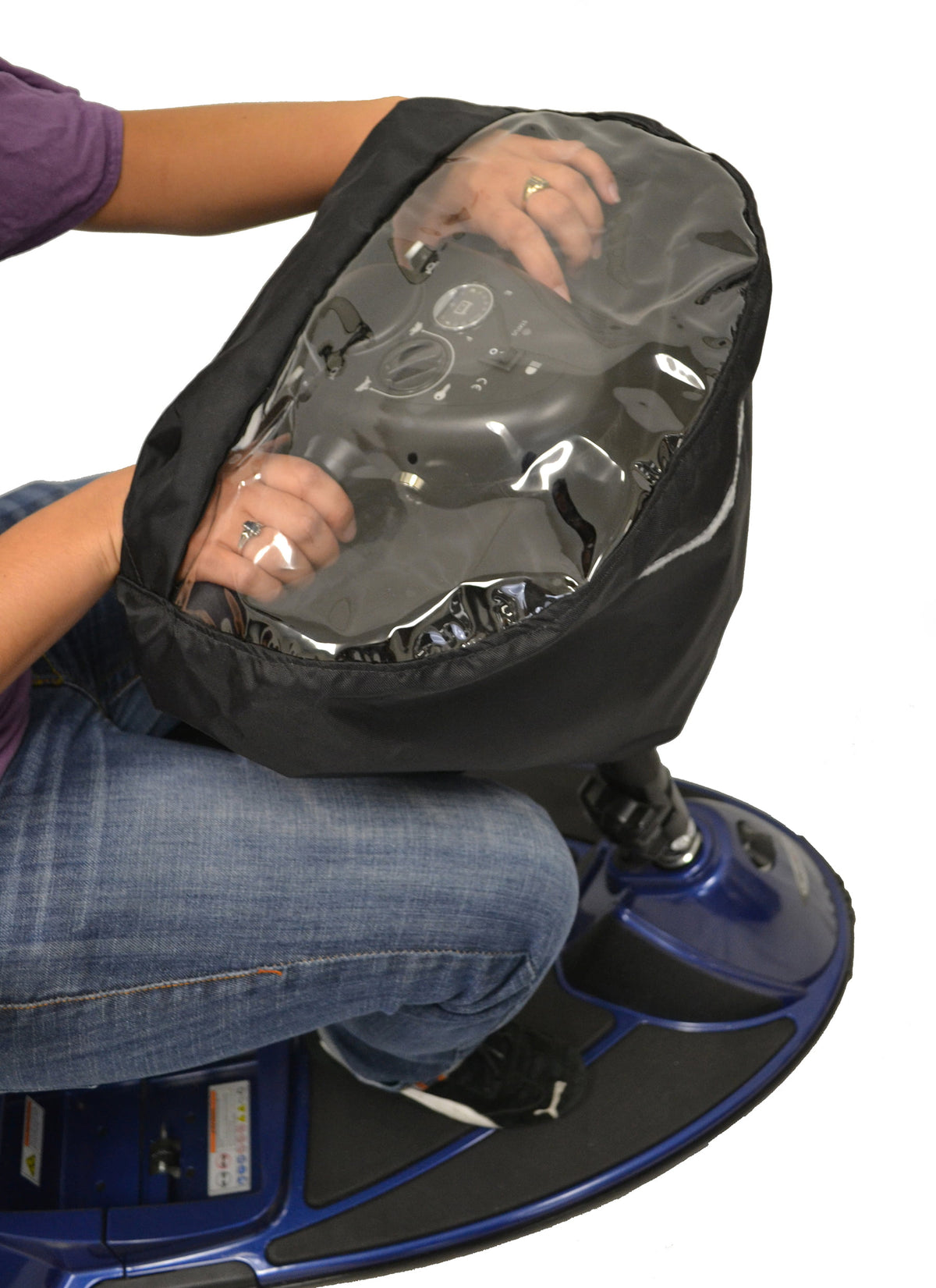 Person fitting a Diestco black water-resistant tiller cover over a mobility scooter's handlebars, with the speed dial, key, and battery gauge visible through the clear vinyl window