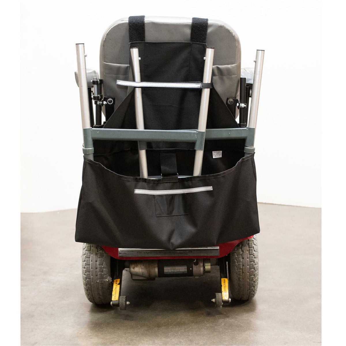 Rear view of the Diestco Walker Holder on a scooter seatback with a folded walker secured by hook-and-loop straps and reflective strips