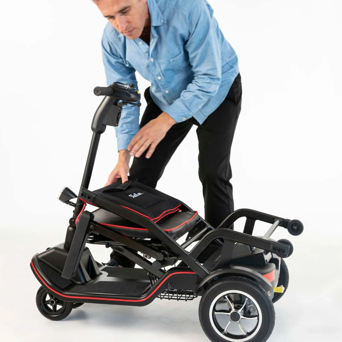 Man lowering the Feather Scooter tiller down over the folded seat to complete the fold