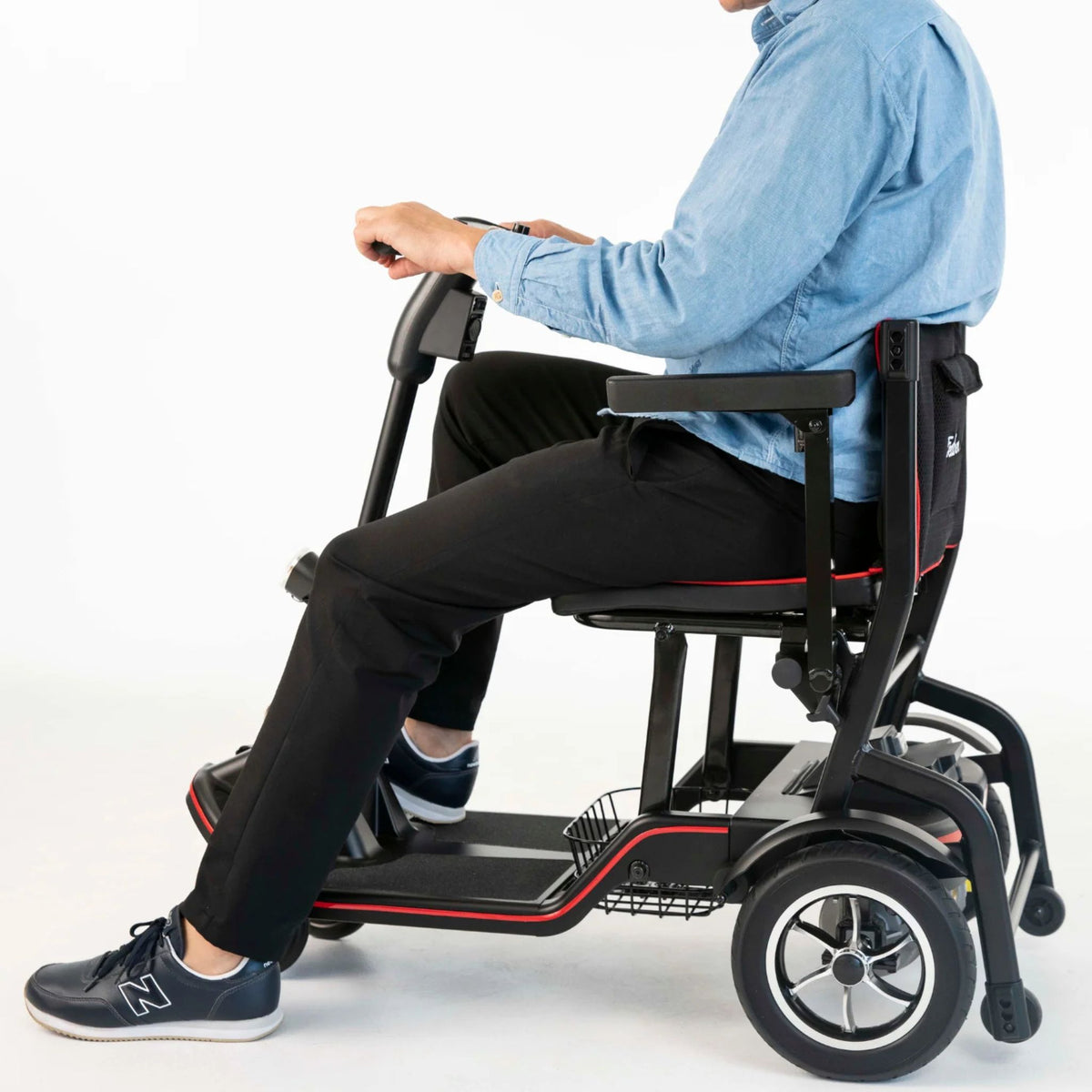 Side view of a man seated on the Feather Scooter showing seat height, armrest, tiller reach, and front basket