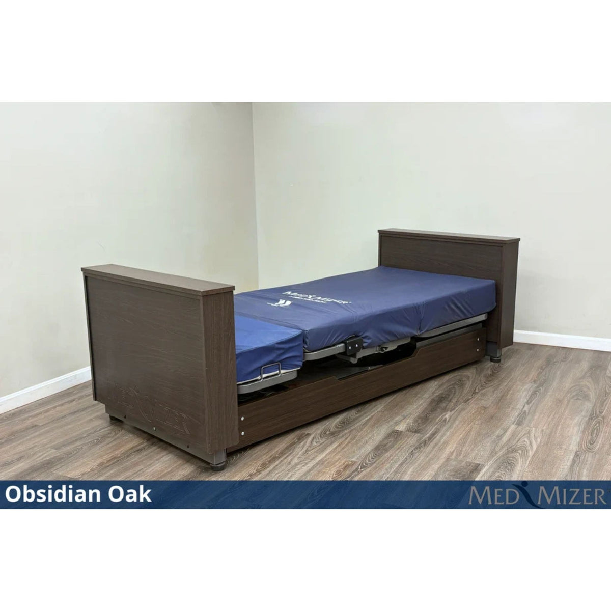 Med-Mizer ActiveCare Deluxe rotating pivot home care bed in Obsidian Oak, lowered flat with a blue mattress