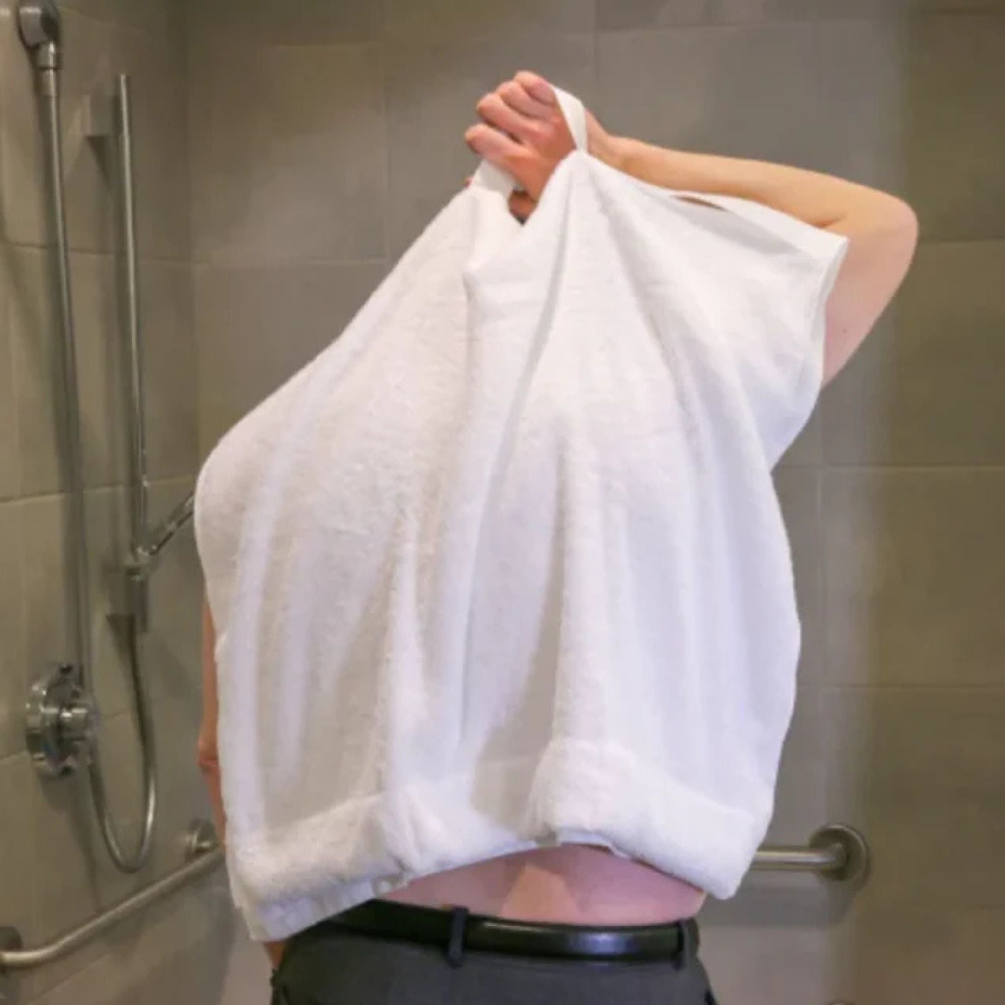 Person using the Mobility Towel by Kay Inspired to dry their back independently by pulling the sewn handles over the shoulders.