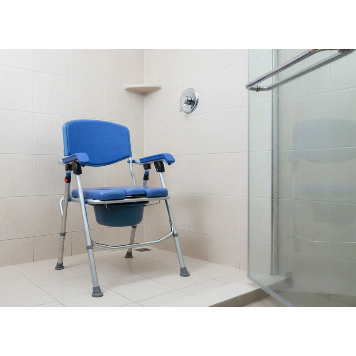 UltraCommode padded commode chair used as a shower chair inside a beige tiled shower stall with glass door