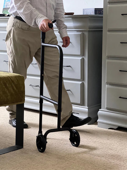 Person using a black walker in a room with white cabinets.