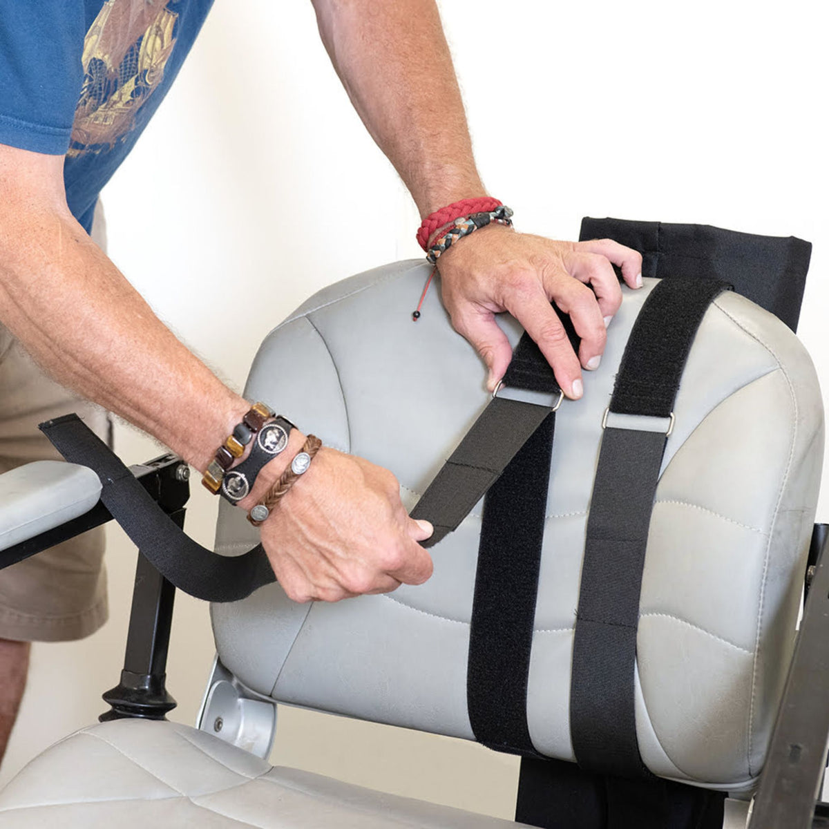 Person fastening the hook-and-loop straps of the Diestco E-Tank Holder around a power wheelchair seatback