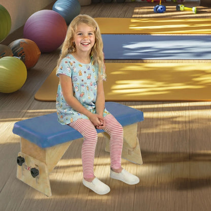 Little girl seated with feet flat on adjustable Axis therapy bench in a pediatric therapy gym
