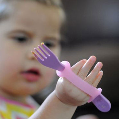Baby using a pink EaZyHold cuff to hold a small purple fork while learning to self-feed