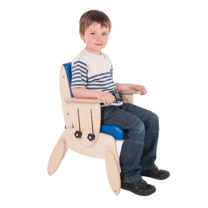 A smiling boy sitting in a blue Smirthwaite Juni postural chair with the padded lap strap fastened.