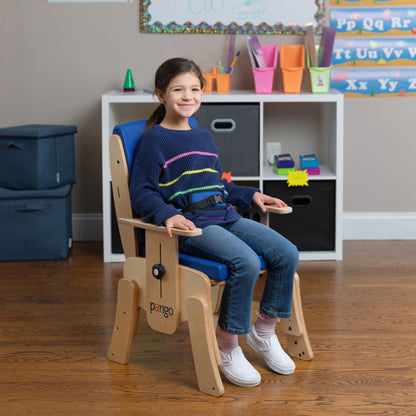 Smiling girl seated upright in a blue Circle Specialty Pango school chair with padded pelvic belt and wooden armrests