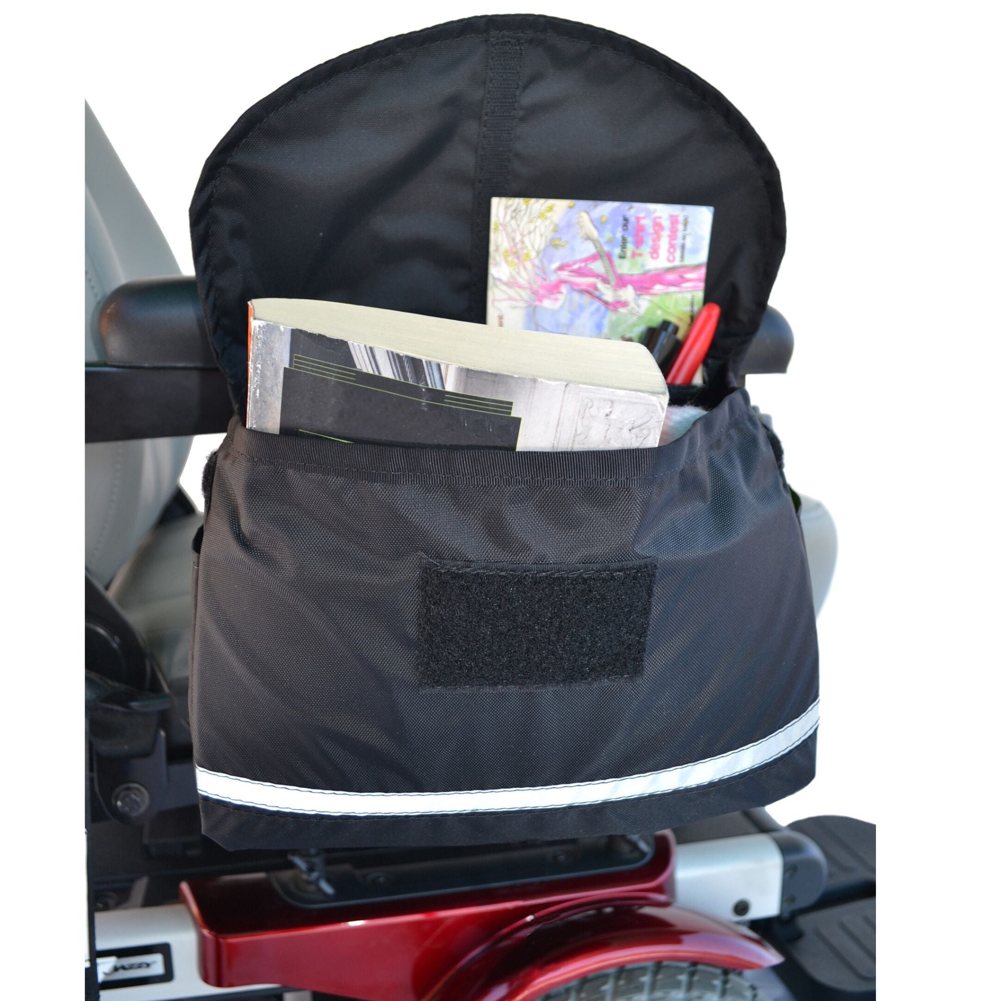 Diestco Deluxe Saddle Bag on an armrest holding a notebook and pens, showing the front and side pockets