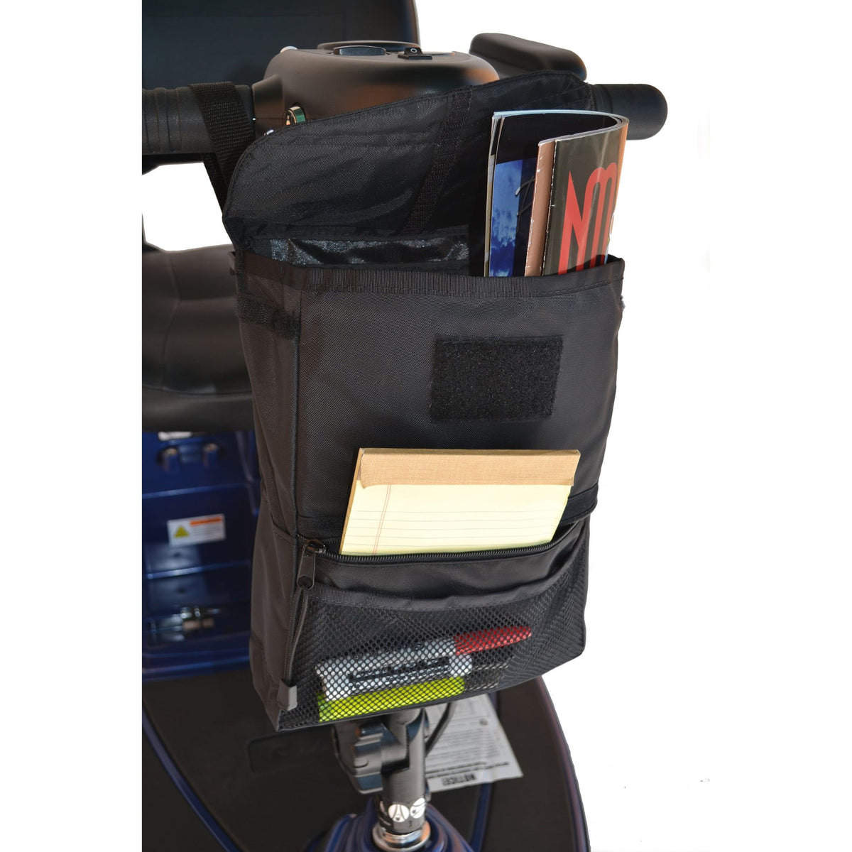 Side view of the Diestco Deluxe Tiller Bag on a mobility scooter tiller, showing the main compartment, zippered front pocket with pull ring, side mesh pocket, and hook-and-loop closure