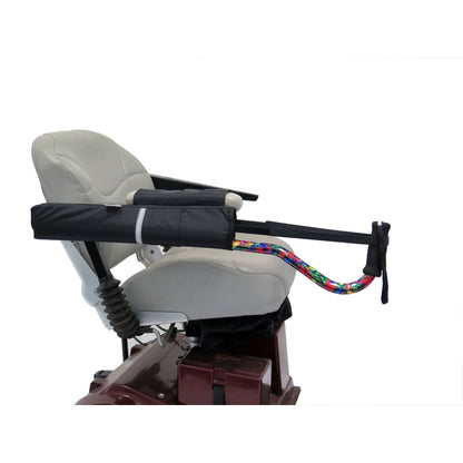 Side view of the Diestco horizontal Cane Holder on a scooter armrest, with a colorful cane secured by the adjustable strap