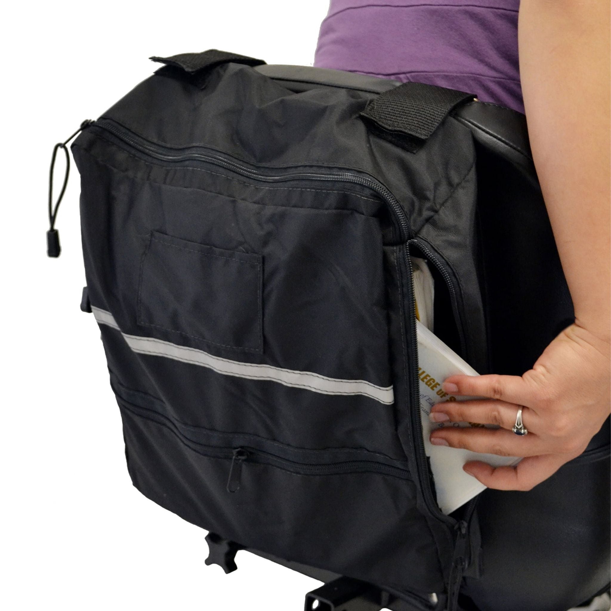 Person reaching into the open side zipper of a black Diestco Side Access Seatback Bag on a wheelchair to grab papers