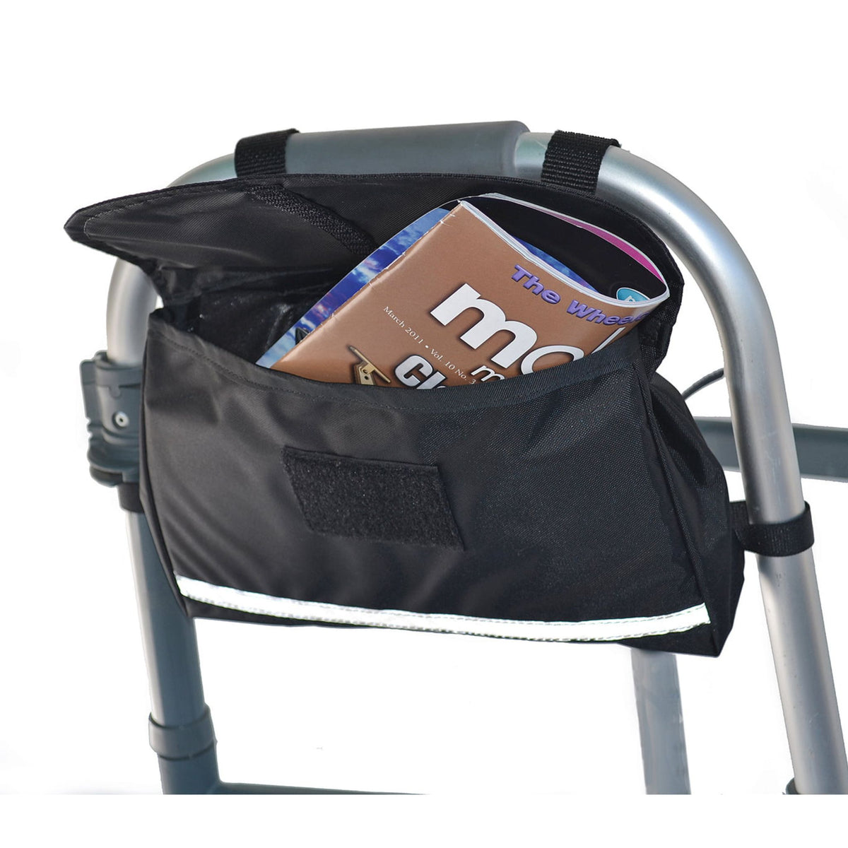 Diestco Standard Walker Bag strapped to a folding walker's front crossbar, flap open with a magazine inside, hook-and-loop closure and reflective strip