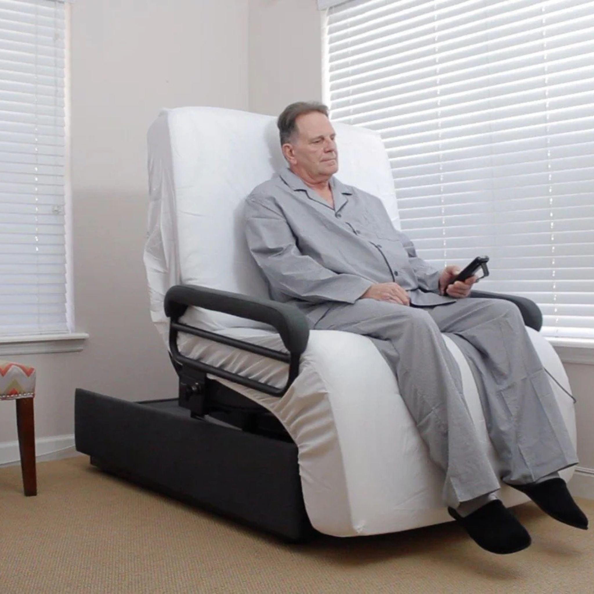 ENVYY Sleep-to-Stand adjustable bed for elderly by Platinum Health.  Older person using the remote control and padded support rails to assist with safer bed exit and comfortable seated positioning at home.