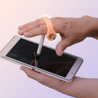 Hand using a orange EaZyHold cuff to hold a stylus while writing on a tablet, easing grip strain