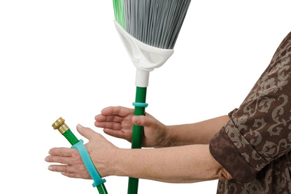 Woman using teal EaZyHold cuffs to grip a broom handle and a garden hose, keeping both secure with a relaxed grip