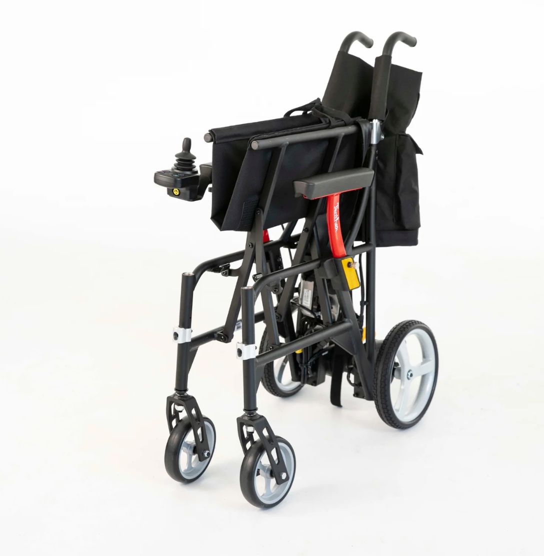 Folded Feather Power Chair standing upright with push handles raised and joystick in place