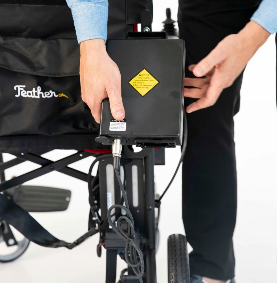 Feather Power Chair lithium battery pack mounted behind the seat with the charger cable plugged in