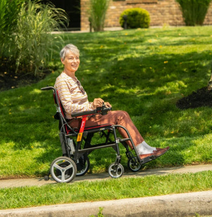 Woman driving a Feather Power Chair along a sidewalk beside a lawn