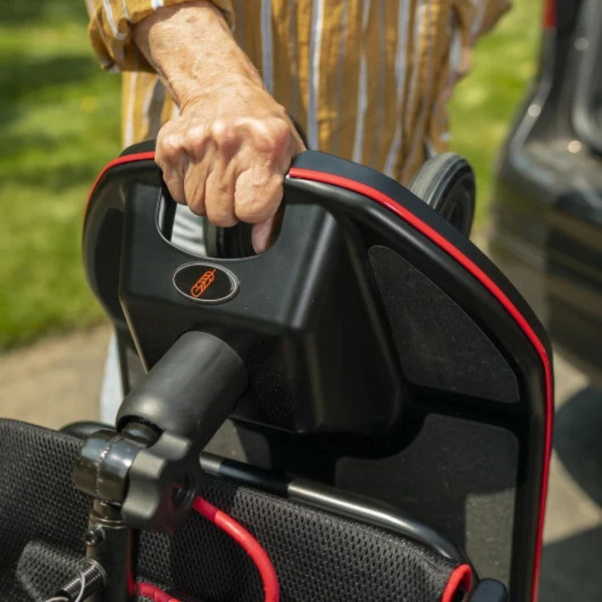 Close-up of a hand gripping the built-in carry handle on the folded Feather Scooter