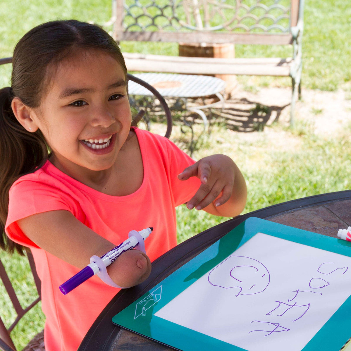 Smiling girl using a white EaZyHold cuff on her forearm to hold a marker and write