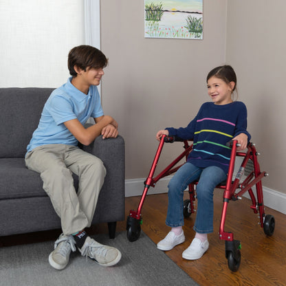 Girl resting on the flip-up seat of a red Klip posterior walker while talking with her brother