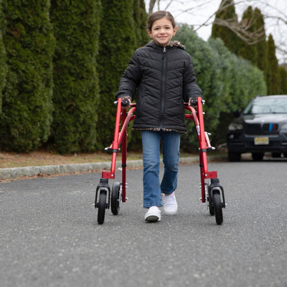 Girl walking on a paved road with a red Circle Specialty Klip posterior walker with large 8 inch front wheels