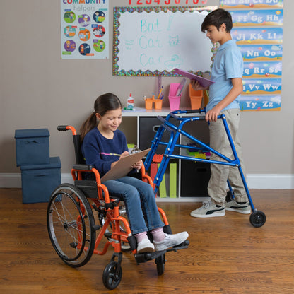 Boy using a blue Klip posterior walker in a classroom next to a girl in a pediatric wheelchair