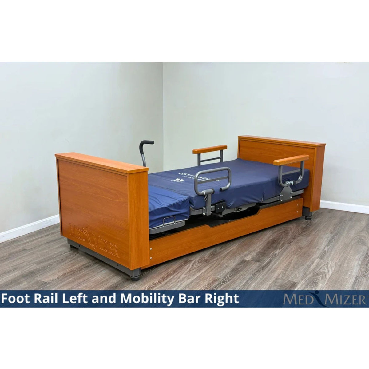 Med-Mizer ActiveCare Deluxe home care bed lowered flat with a foot rail on the left and a mobility bar on the right