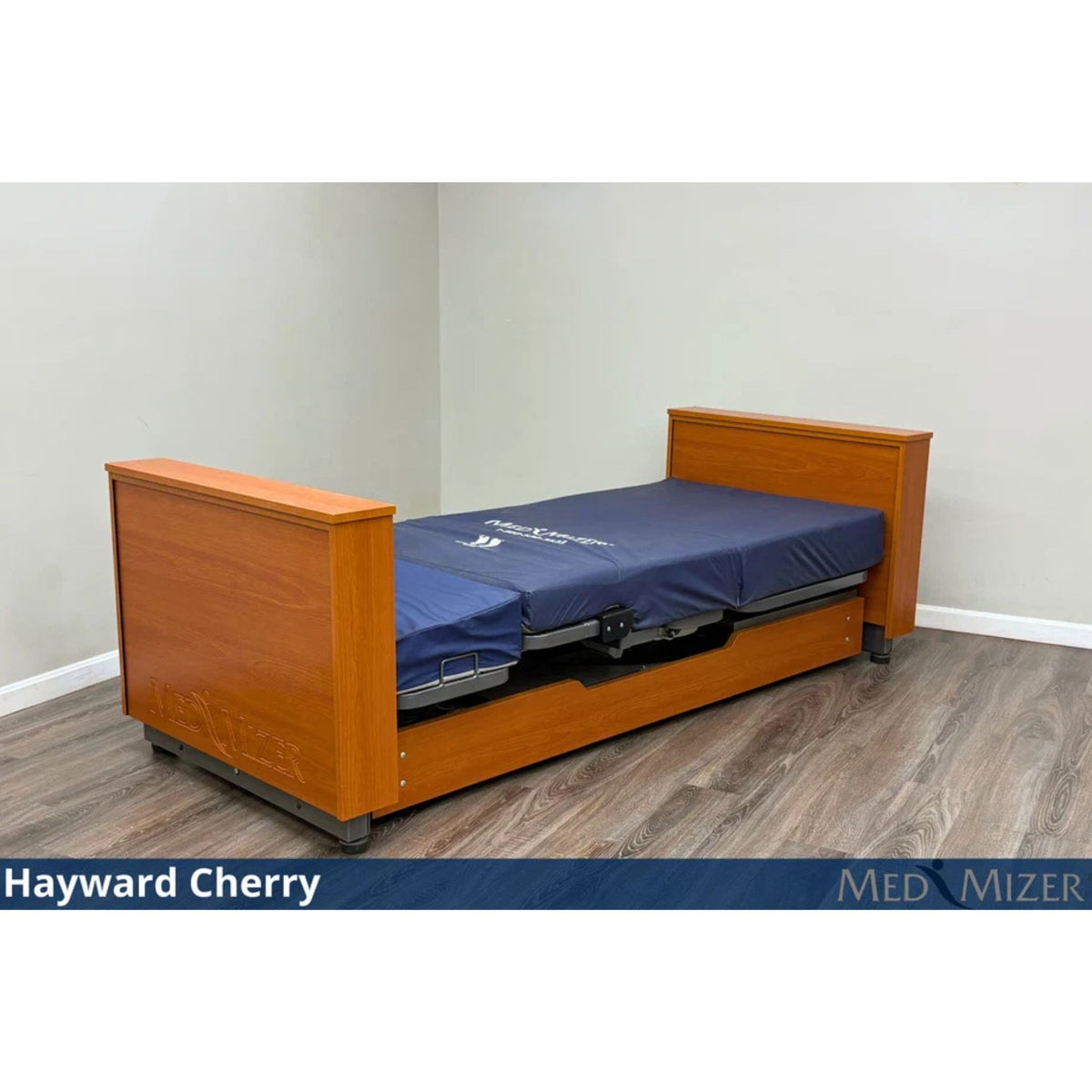 Med-Mizer ActiveCare Deluxe rotating pivot home care bed in Hayward Cherry, lowered flat with a blue mattress