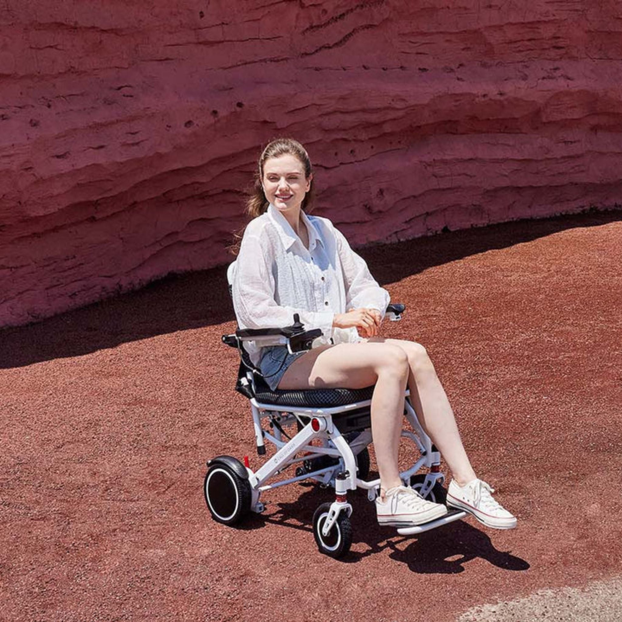 Person riding the OAS Air Pro lightweight electric wheelchair across scenic desert terrain