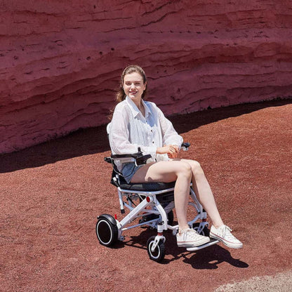 Person riding the OAS Air Pro lightweight electric wheelchair across scenic desert terrain