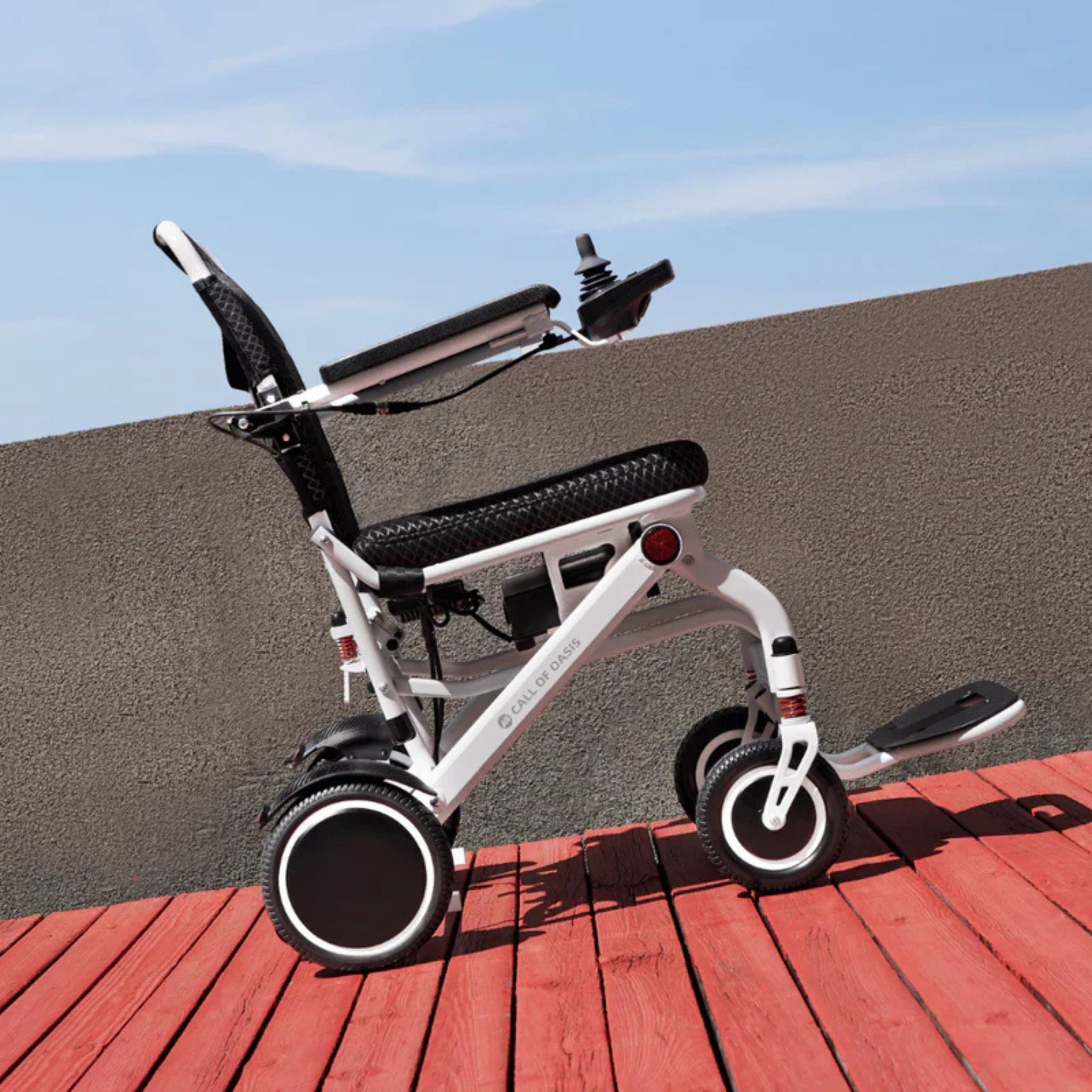 Side profile of the OAS Air Pro lightweight electric wheelchair on a boardwalk near the waterfront