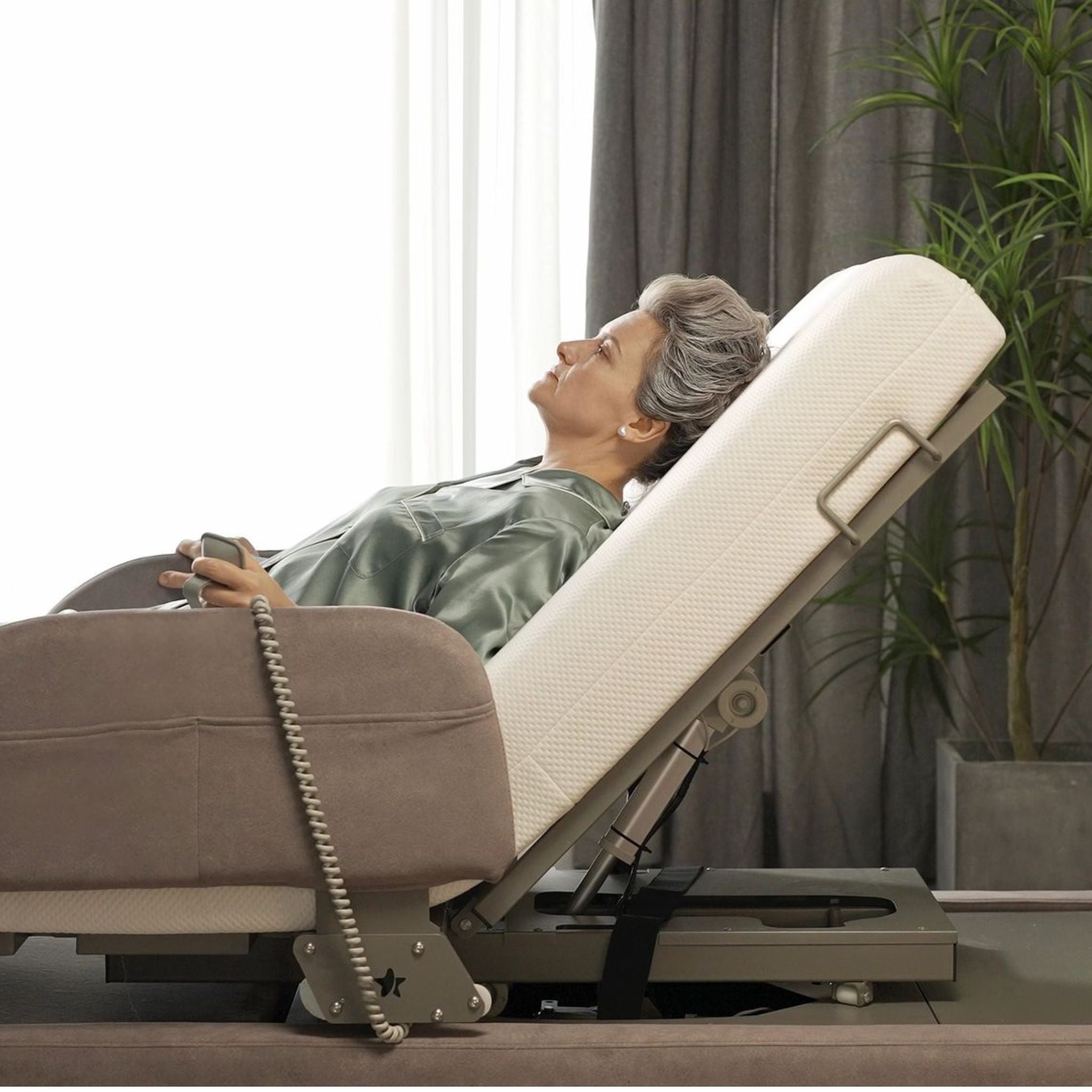 Gray-haired woman reclines comfortably in the raised Arlo bed while holding the remote