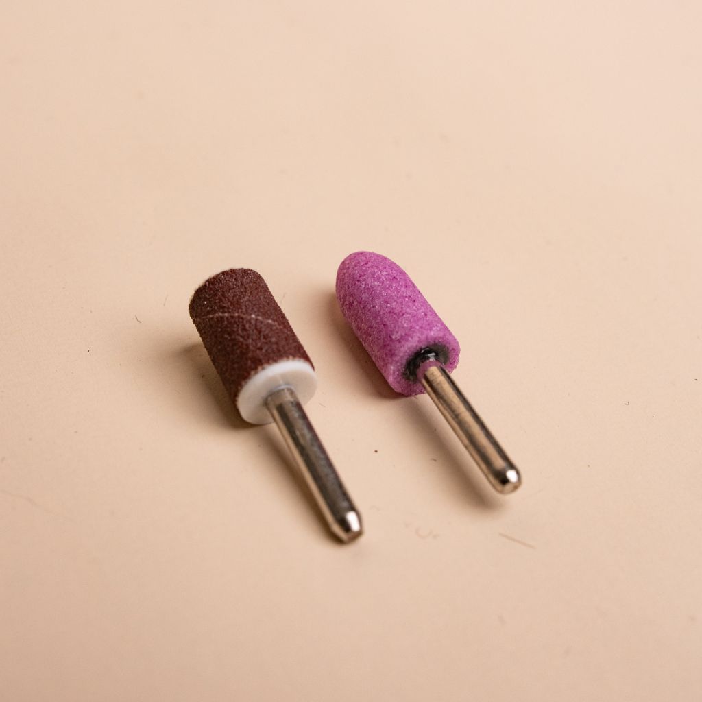 Close-up of two Soulo replacement tips, a brown sanding band and a pink grinding stone tip