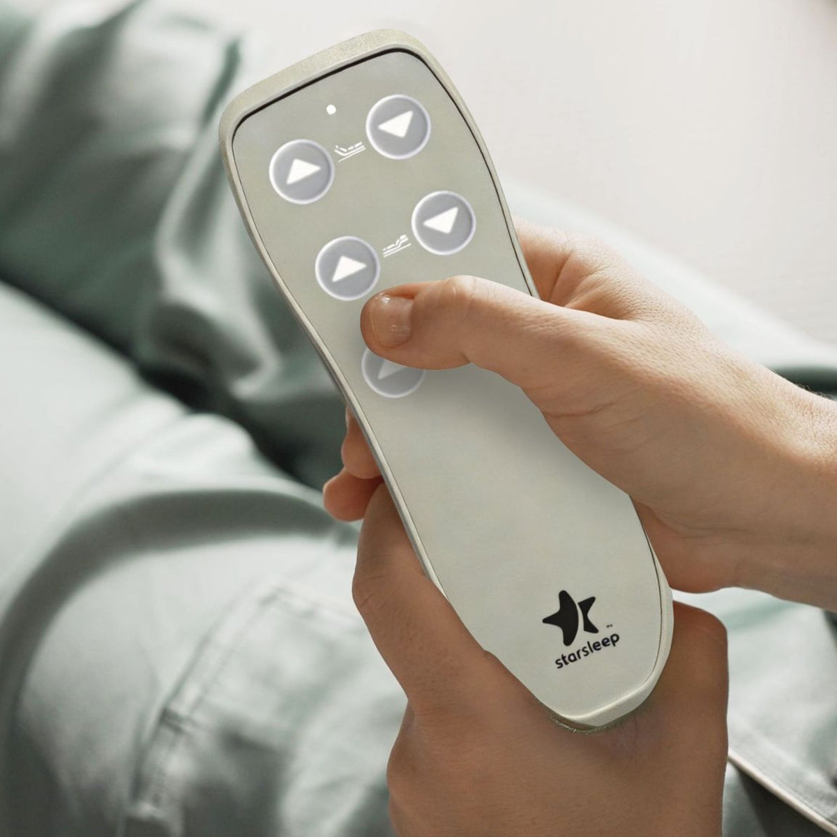 Hand holding the cream StarSleep Arlo remote with buttons to raise the backrest and legs