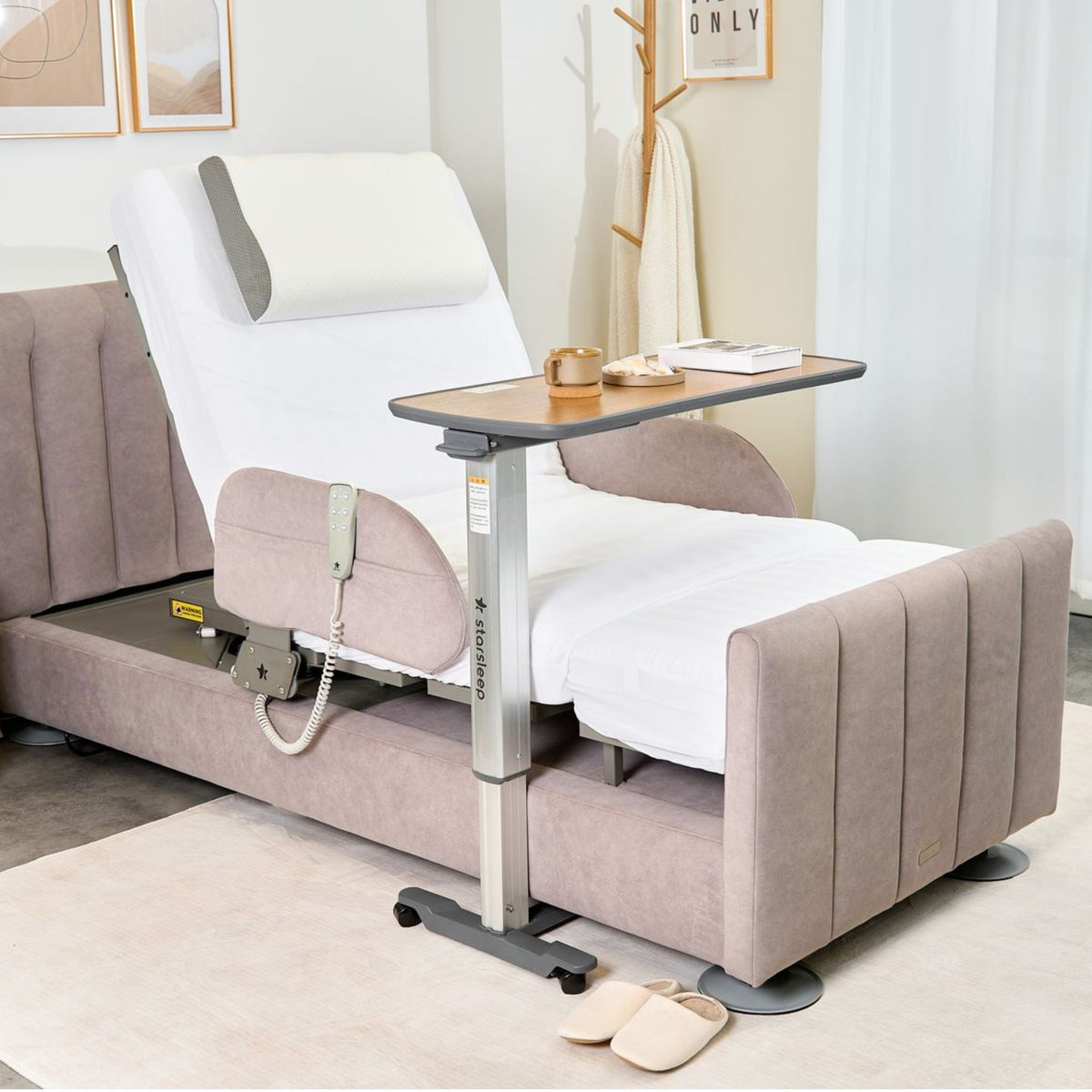 Arlo bed with the backrest raised and a wood overbed table holding a mug and book