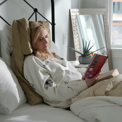 Woman reading in bed using Tausi Vertical Support System for head and neck comfort