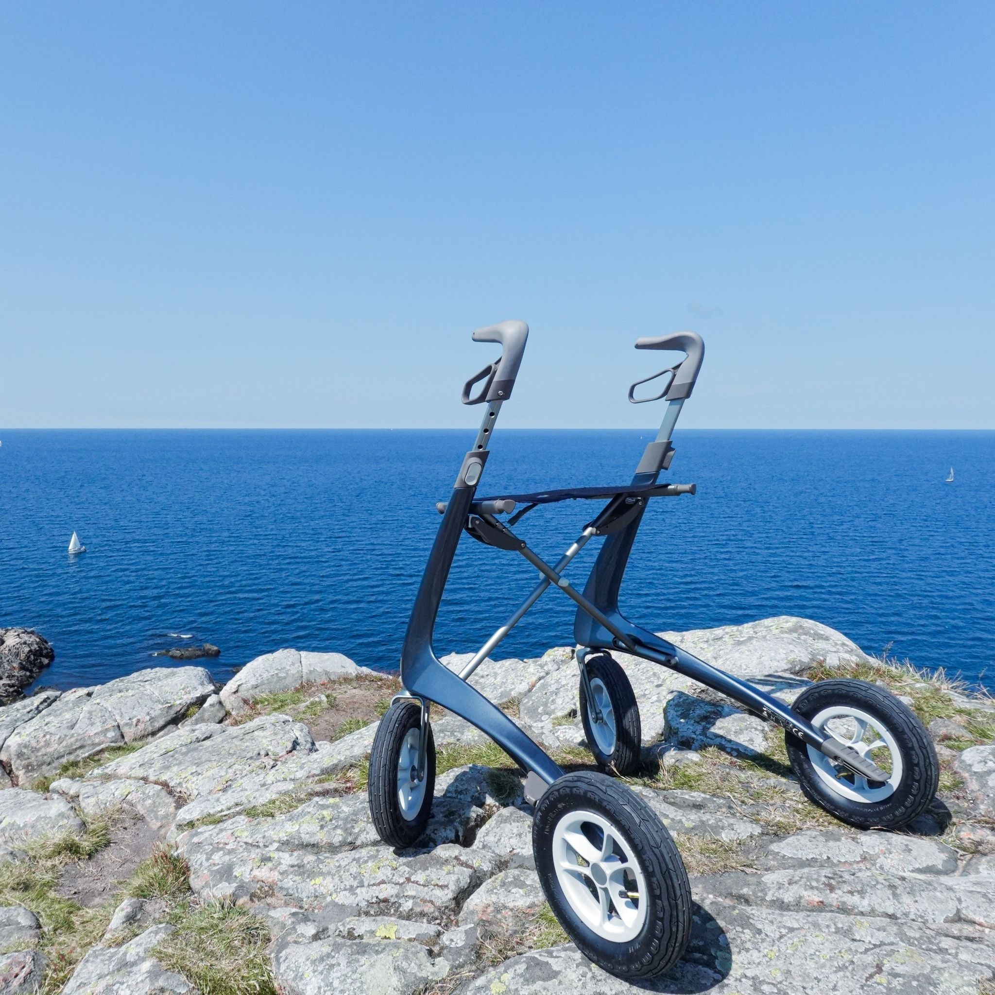 byACRE Carbon Overland rollator positioned on rocky coastal terrain overlooking the ocean.