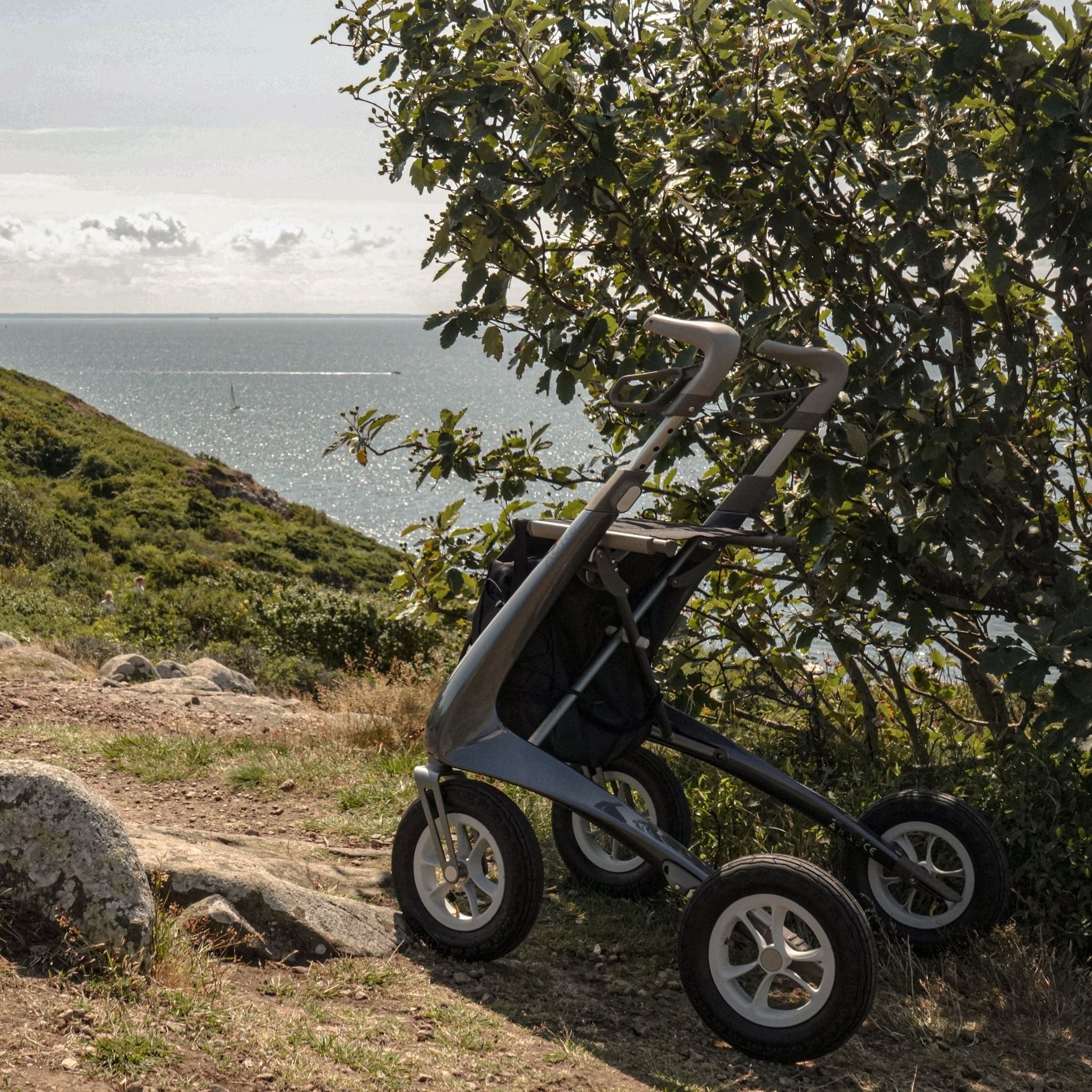 byACRE Carbon Overland all-terrain rollator parked on a scenic coastal trail surrounded by nature.