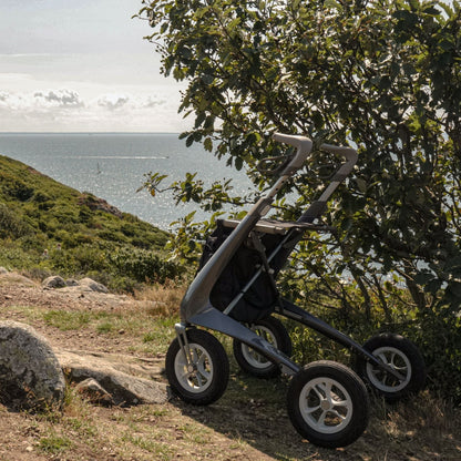 byACRE Carbon Overland all-terrain rollator parked on a scenic coastal trail surrounded by nature.
