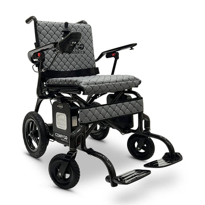 Front angled view of the gray ComfyGO Phoenix Carbon electric wheelchair featuring a carbon fiber frame, padded seat, joystick controller, foldable design, and airline-approved travel-ready mobility system.