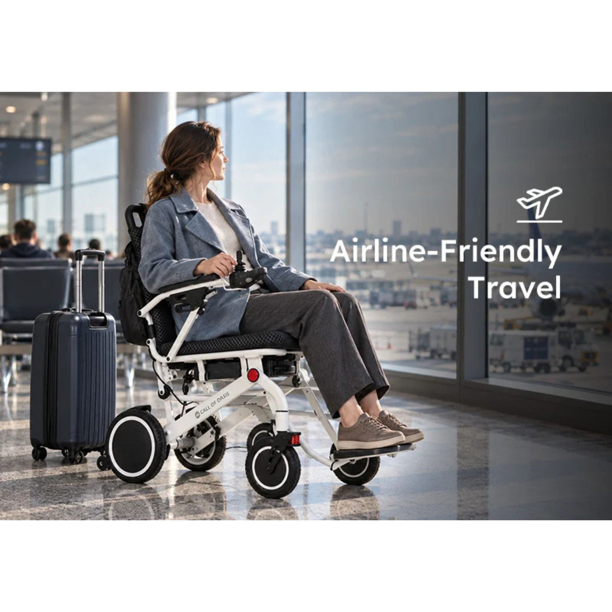 Woman seated in the OAS Air Pro 2027 electric wheelchair at an airport gate with a carry-on suitcase, airline-friendly travel